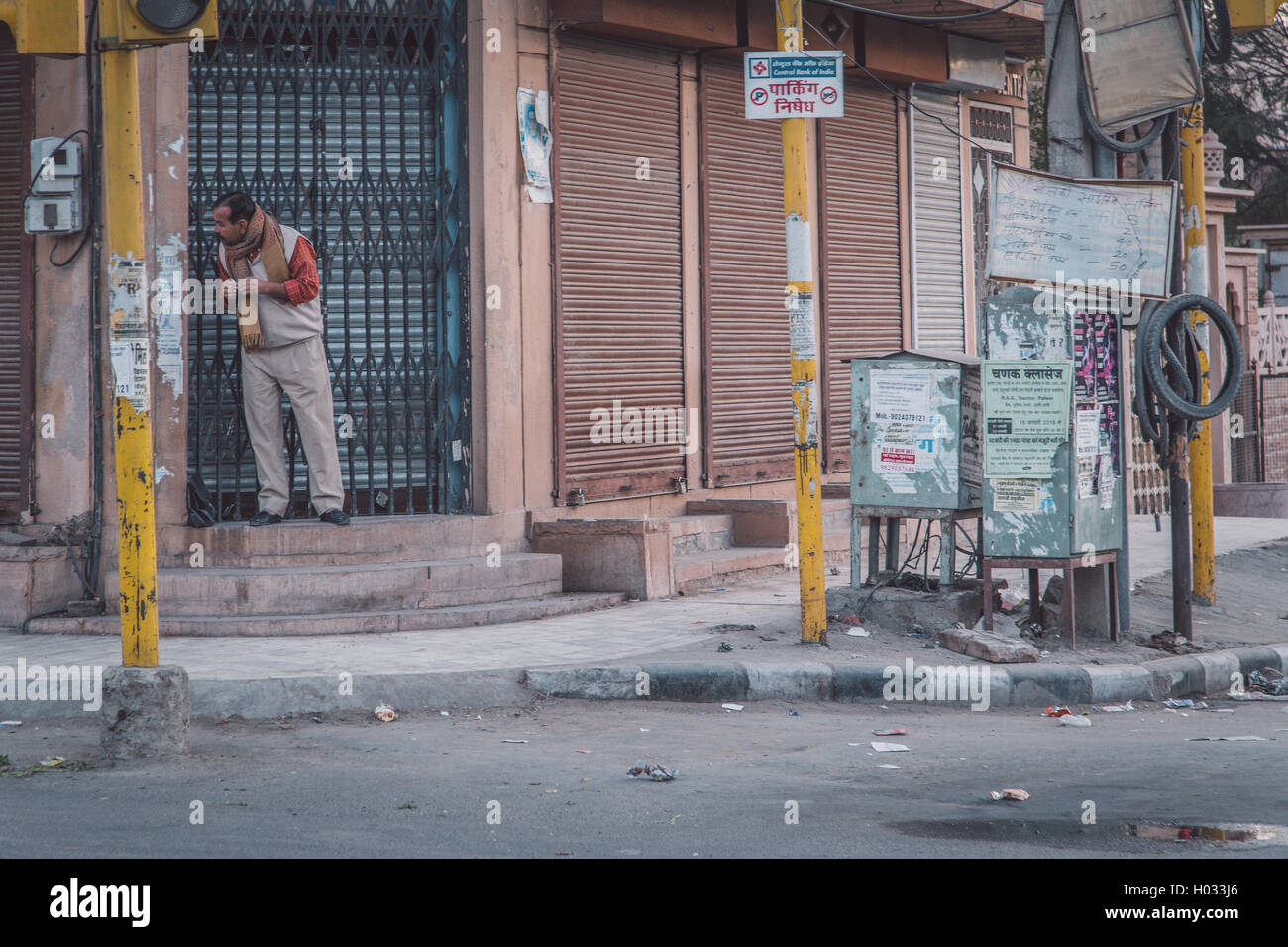 JODHPUR, INDIA - 12 FEBRUARY 2015: Man stands on doorway of building in empty street and looks around the corner. Post-processed Stock Photo
