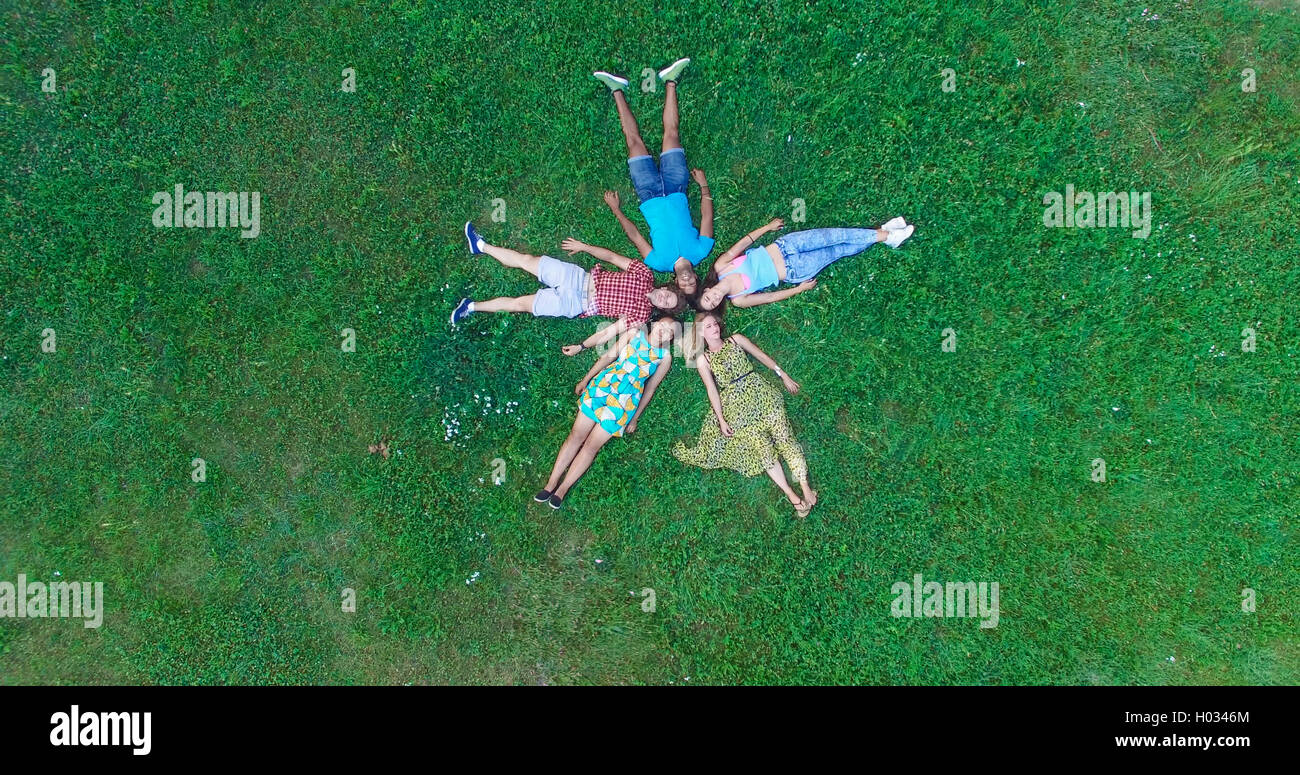 Group of young adults laying in grass in star formation Stock Photo