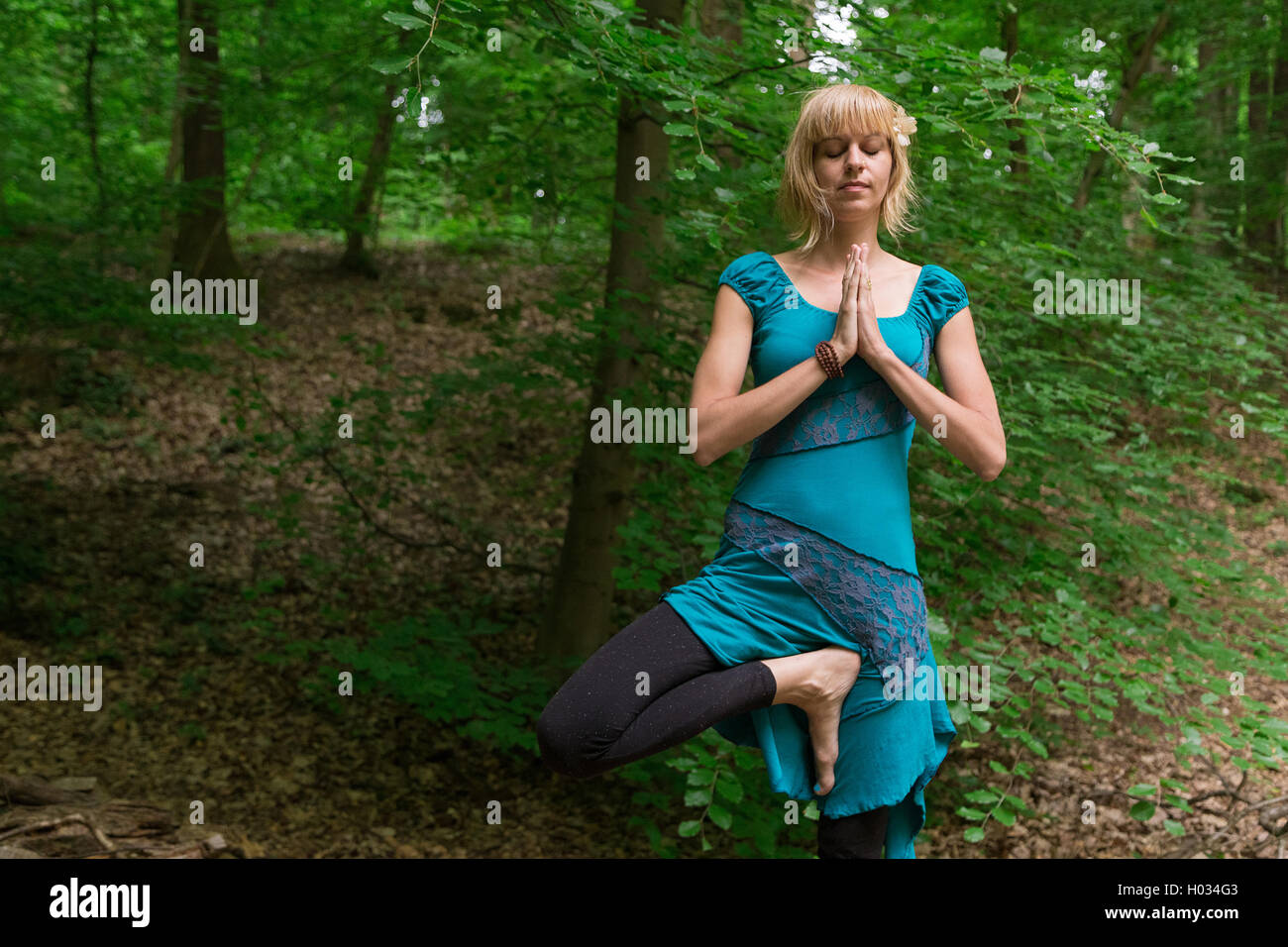 Young woman practicing yoga tree pose in forest Stock Photo - Alamy
