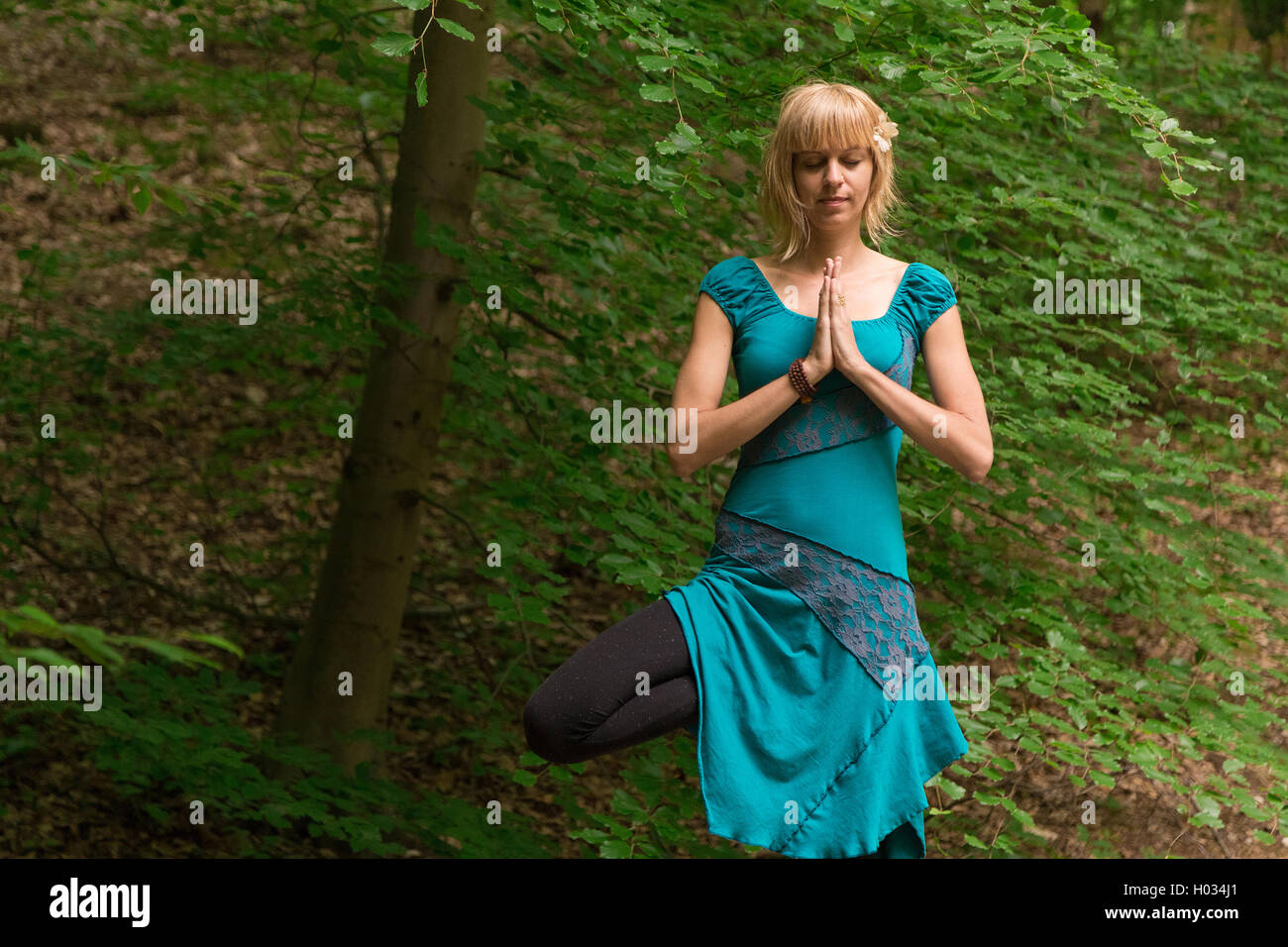 Young woman practicing yoga tree pose in forest Stock Photo - Alamy