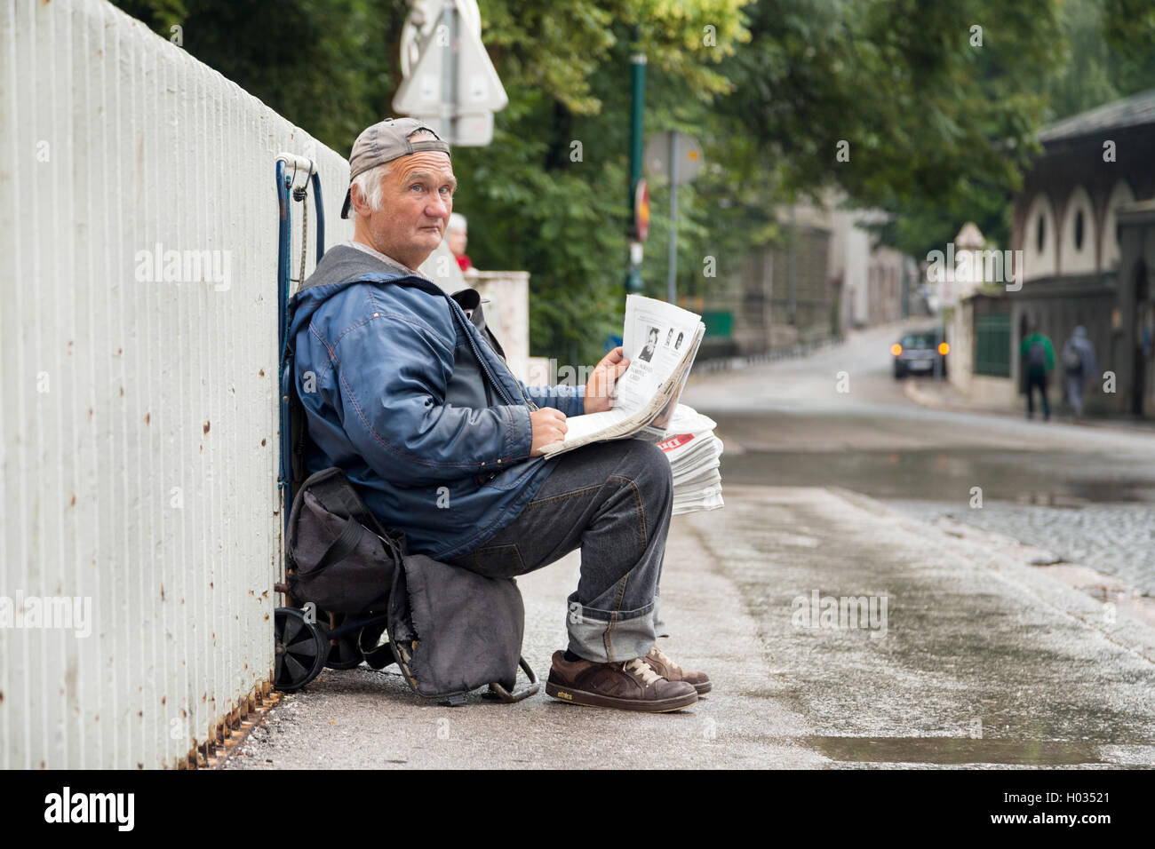 SARAJEVO, BOSNIA AND HERZEGOVINA: JUNE 19, 2014: Elderly newspaper salesman sitting on the cart on street. Stock Photo