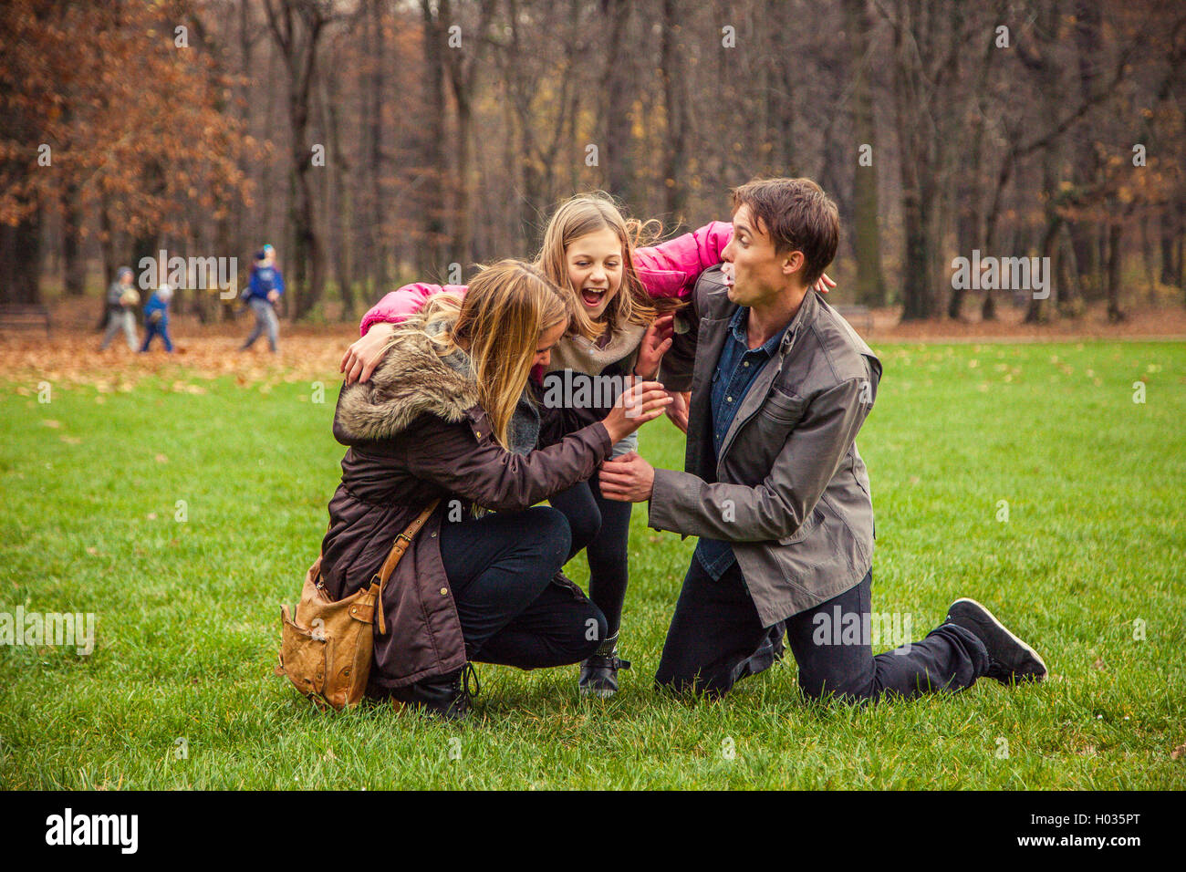 Family of three play around in park. Stock Photo