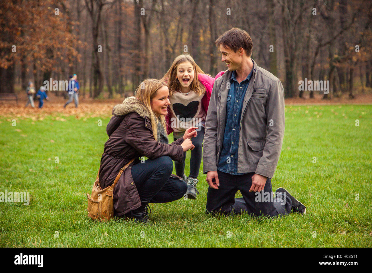 Family of three play around in park. Stock Photo