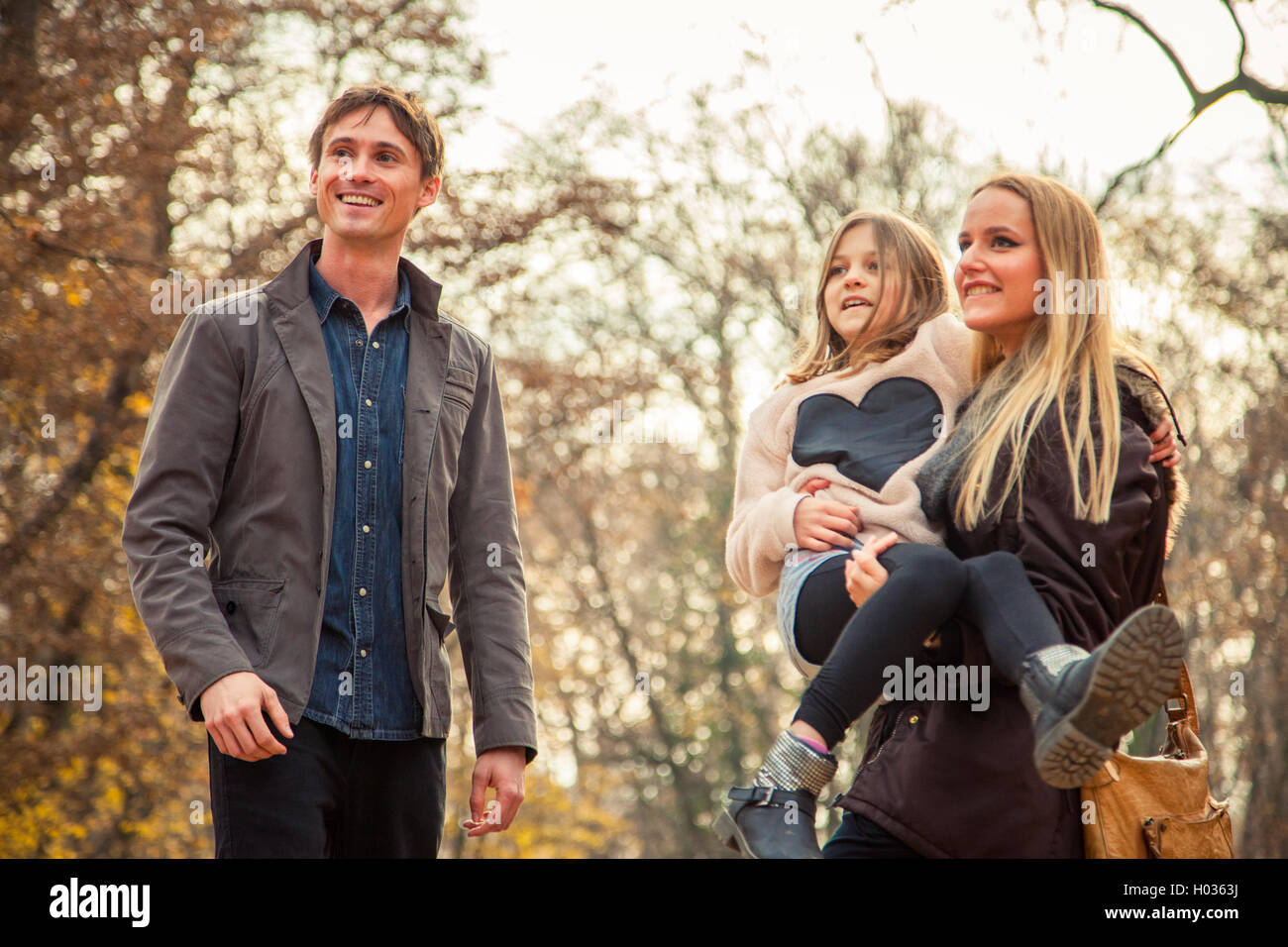 Playfull family of three walk in a park on an autumn day. Stock Photo