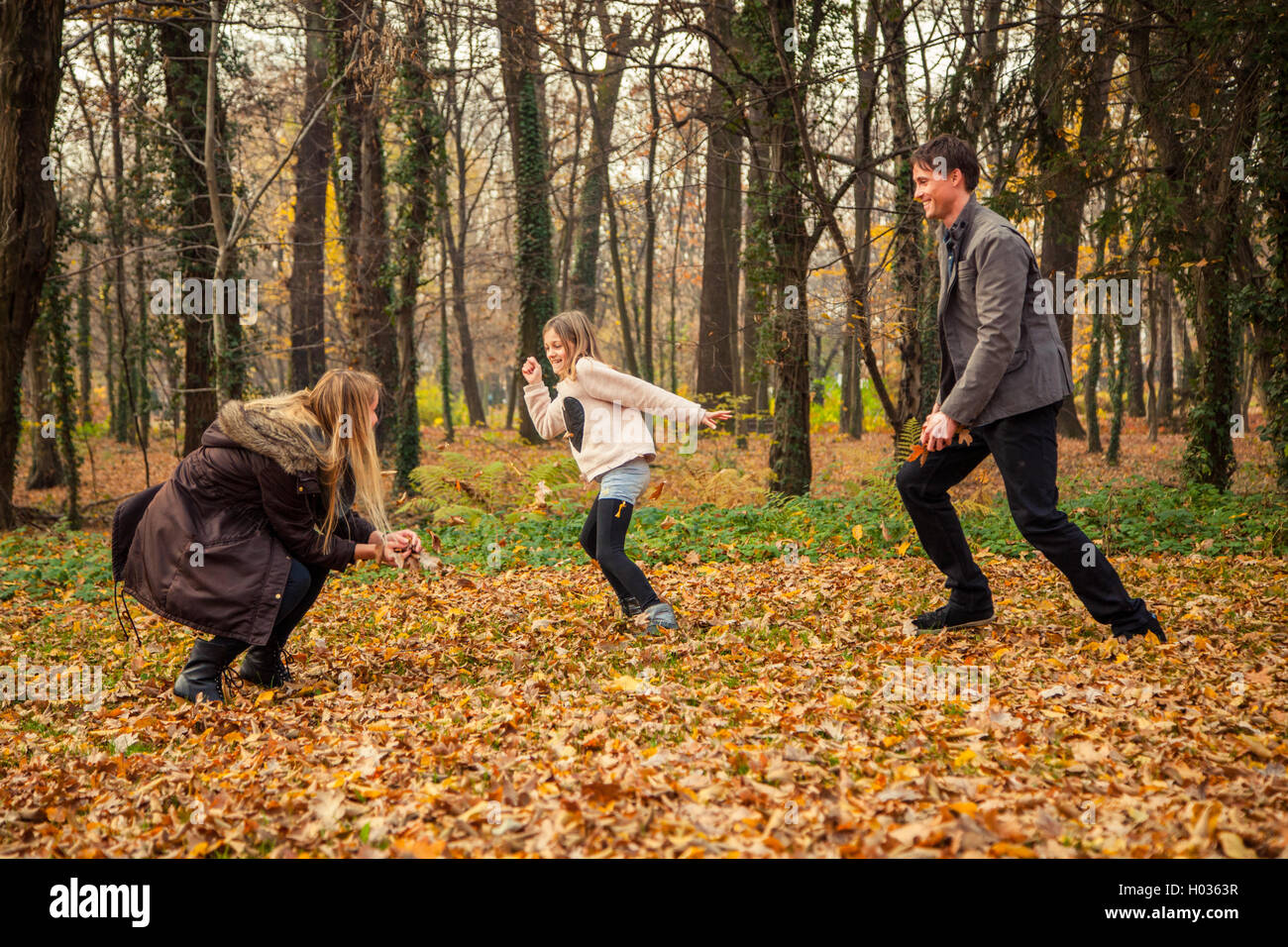 Cheerful family of  three play catch in park. Stock Photo