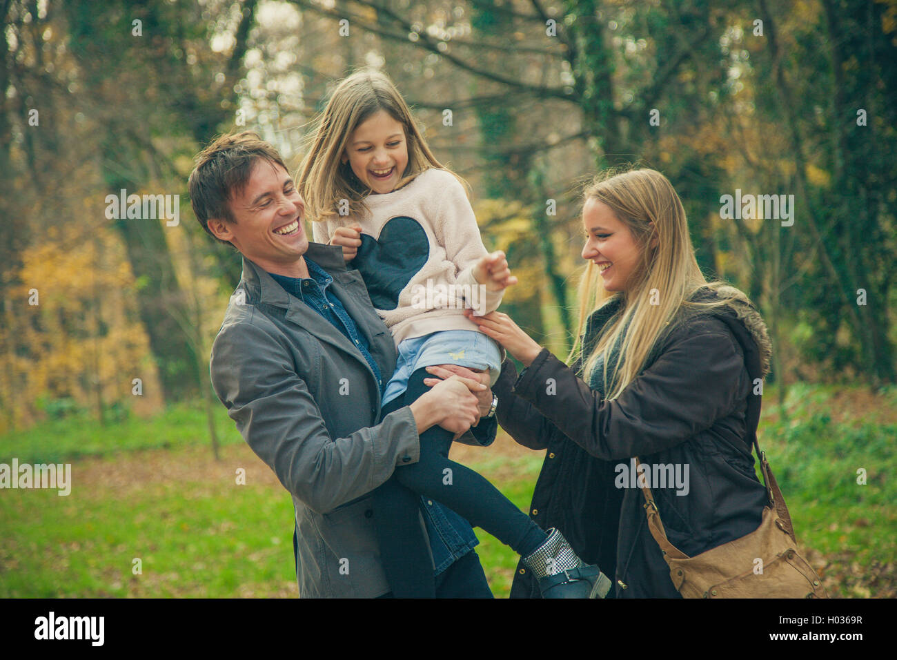Playful family of three walk in a park on an autumn day. Stock Photo
