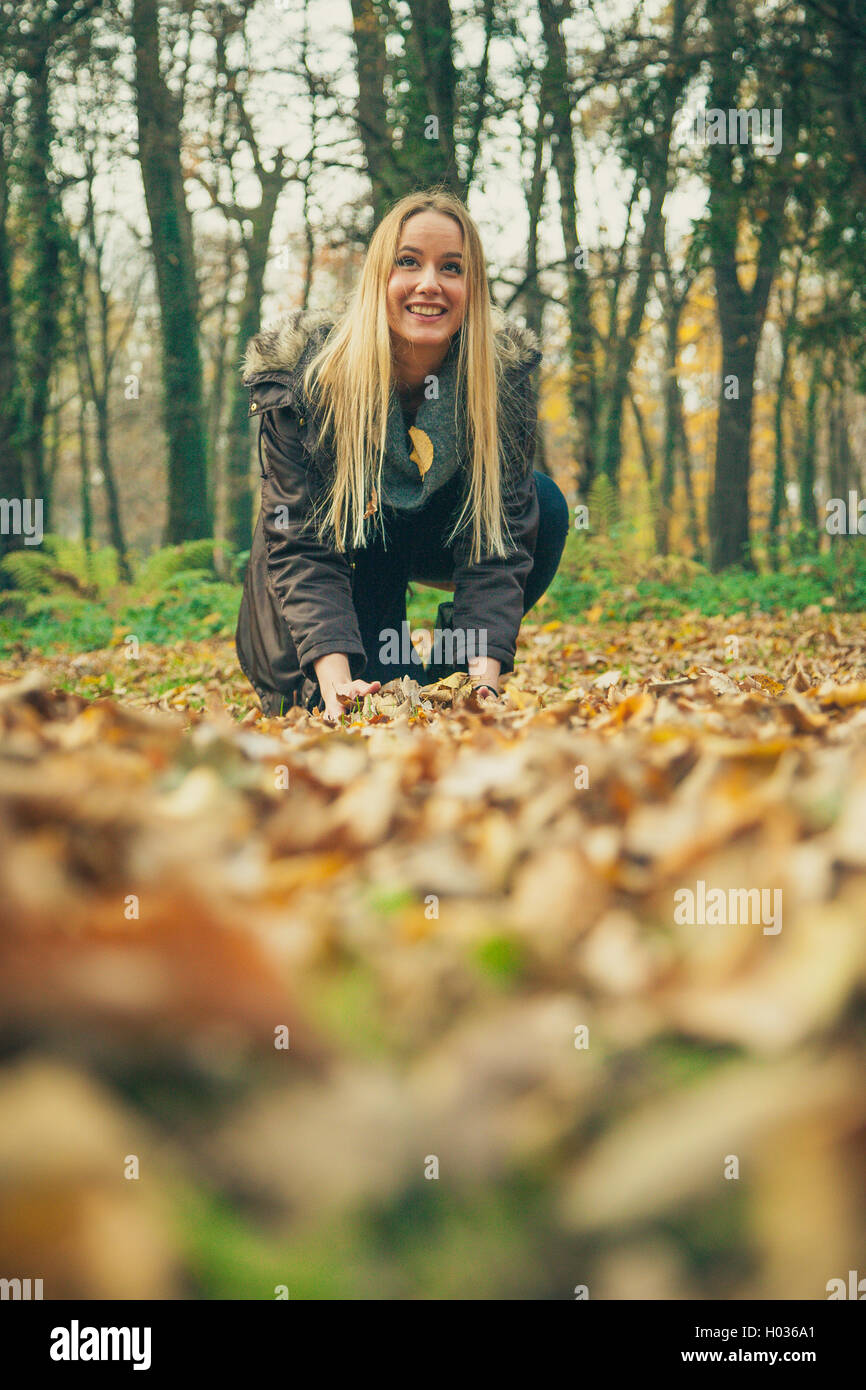 Young woman plays with leave sin park on an autumn day. Stock Photo