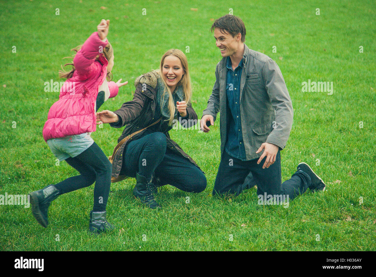 Family of three in park. Daughter cries close by to worried parents. Stock Photo