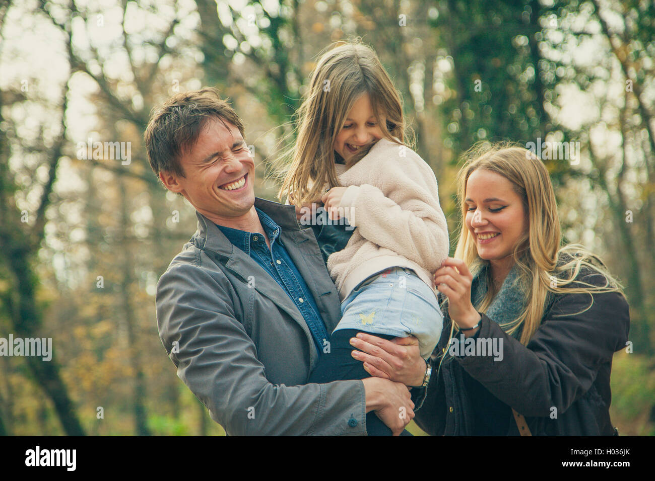 Playful family of three walk in a park on an autumn day. Stock Photo