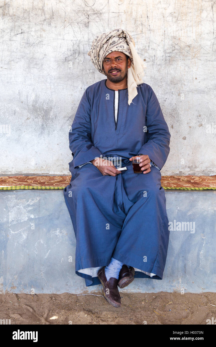 DARAW, EGYPT - FEBRUARY 6, 2016: Local camel salesman holding glass and cigarette. Stock Photo