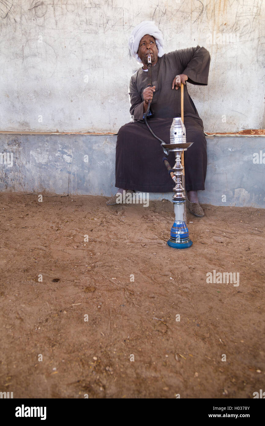 DARAW, EGYPT - FEBRUARY 6, 2016: Local camel salesman smoking shisha pipe. Stock Photo