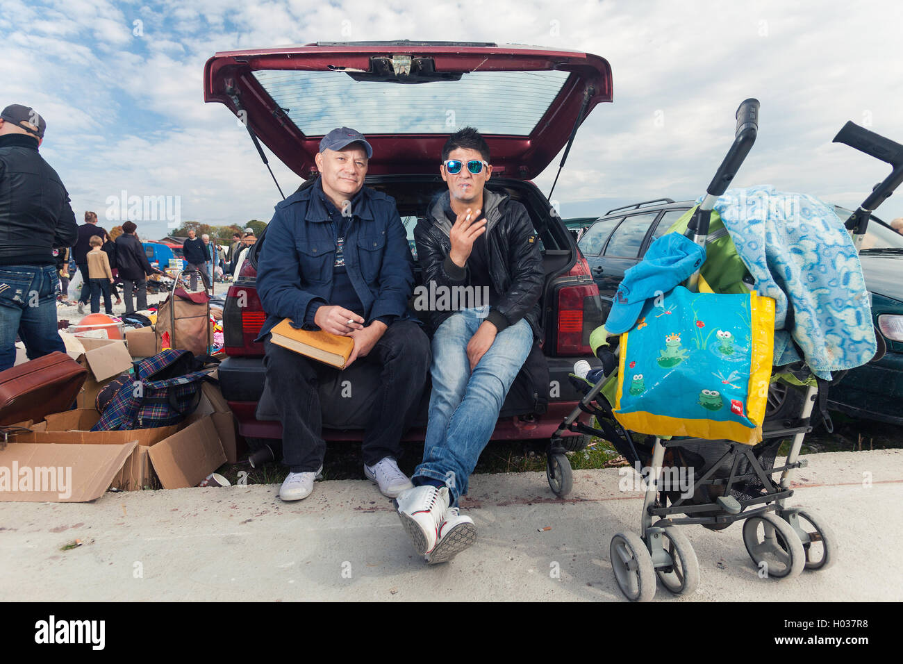 ZAGREB, CROATIA - OCTOBER 20, 2013: Young Roma man sitting at the car trunk with salesman at Zagreb's flea market Hrelic. Stock Photo
