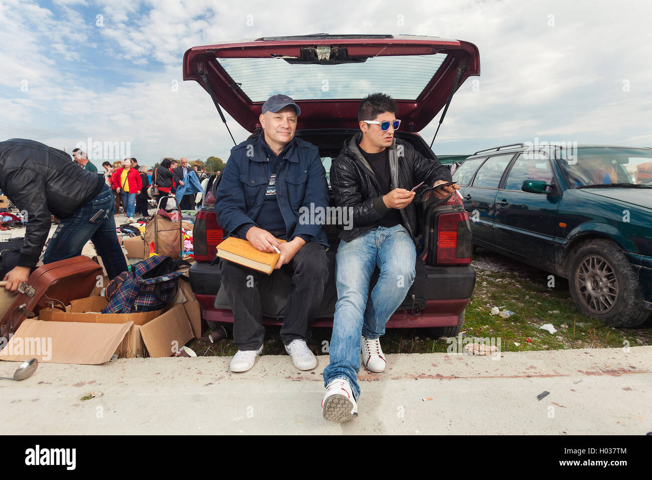ZAGREB, CROATIA - OCTOBER 20, 2013: Young Roma man sitting at the car trunk with salesman at Zagreb's flea market Hrelic. Stock Photo