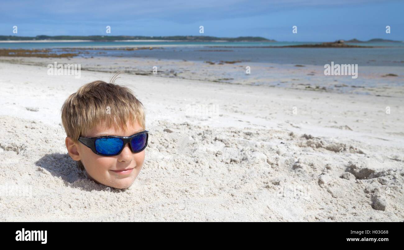 Boy on holiday buried in the sand Stock Photo
