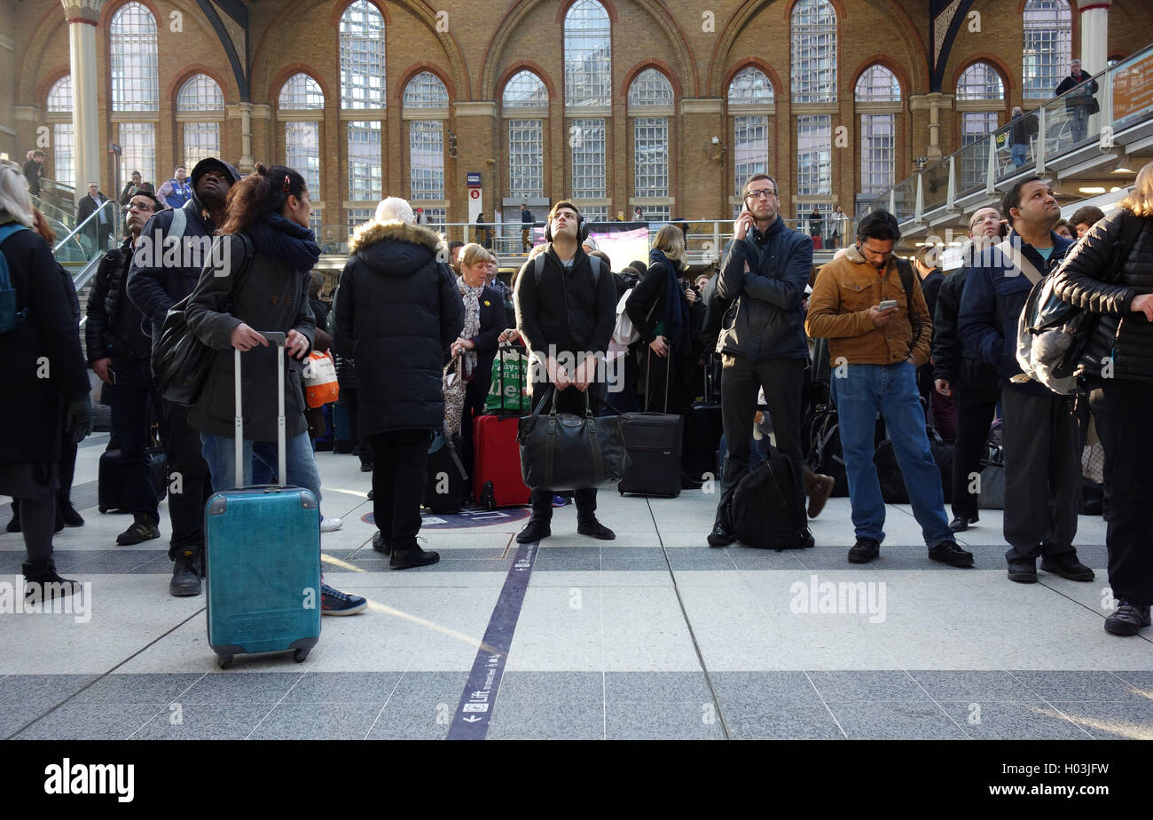 Commuters / passengers looking up at departure board, waiting for delayed trains in Liverpool Street Station, London Stock Photo