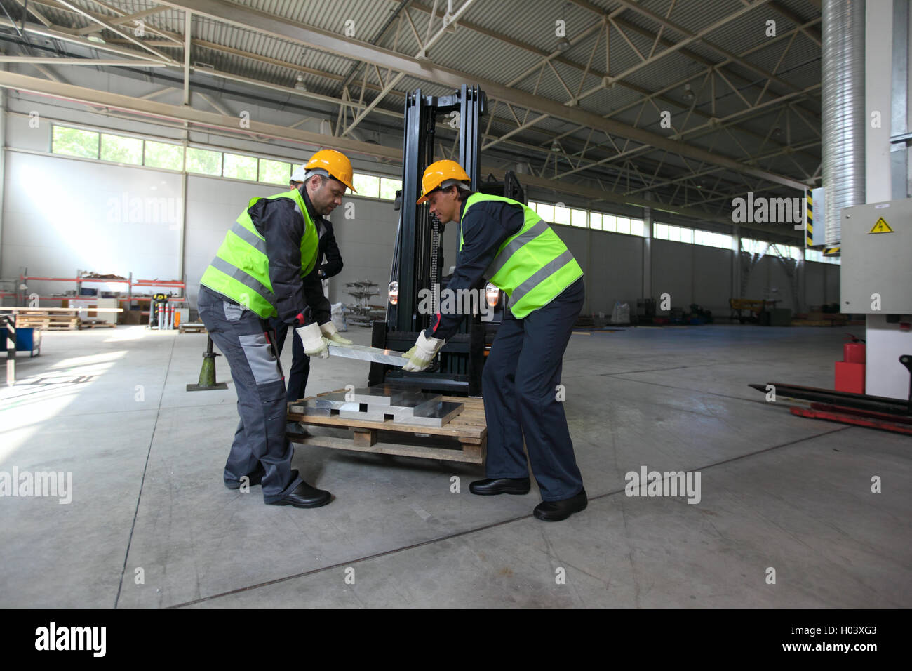 Workers taking aluminium billet at CNC machine shop Stock Photo
