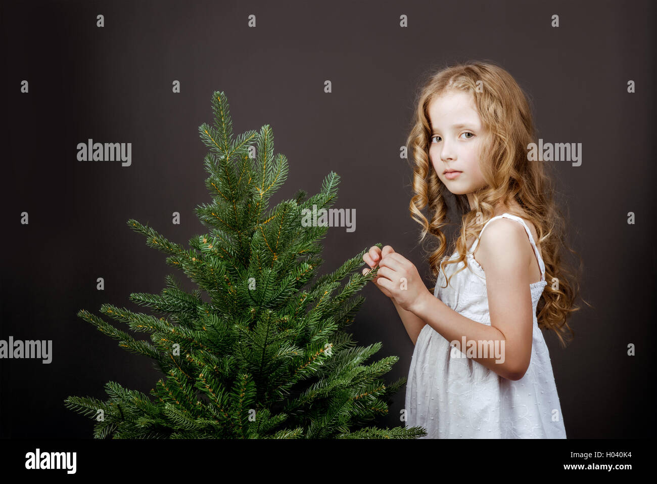 Bright little pretty girl stands near the tree concept Stock Photo