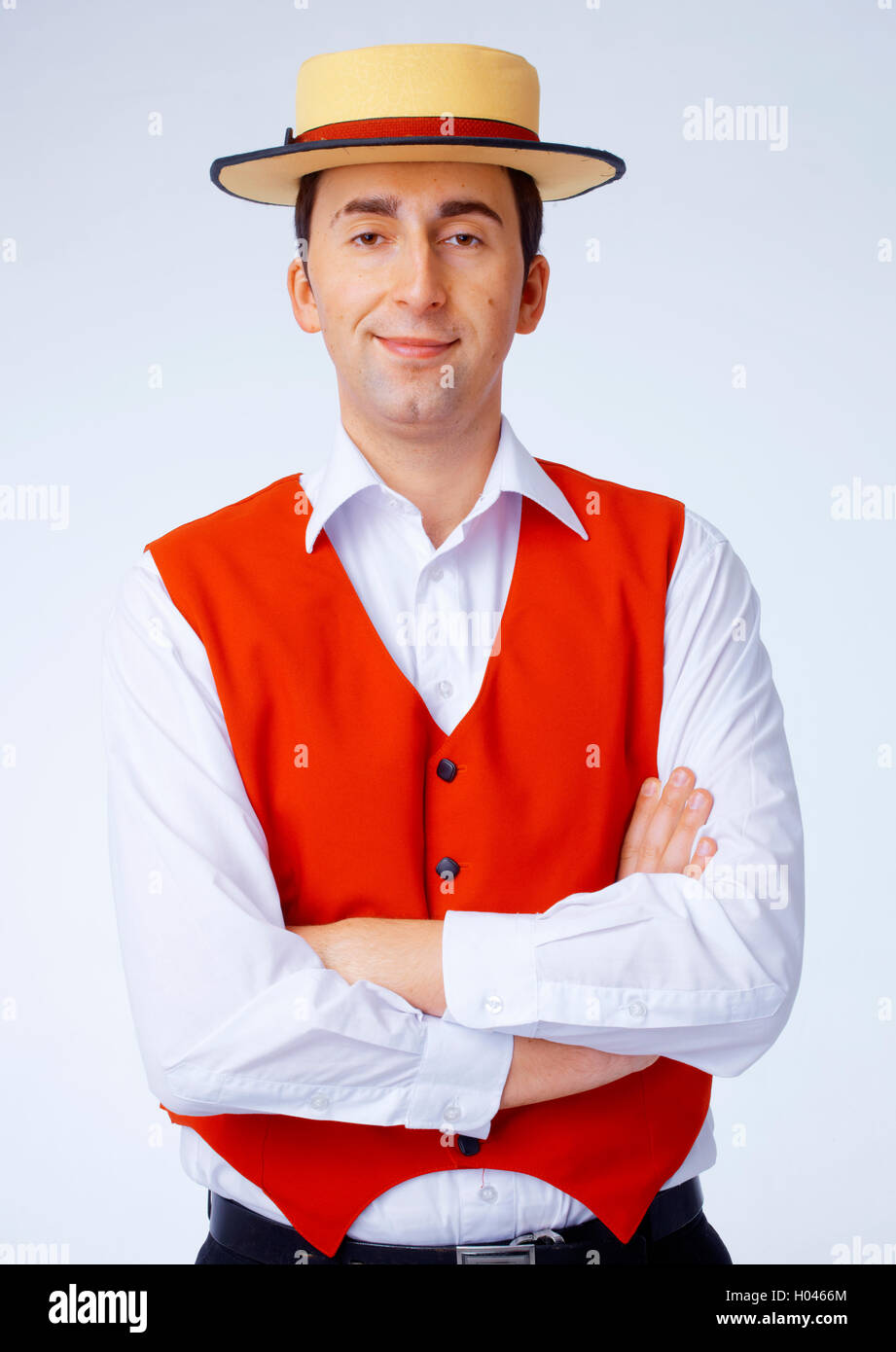 Man in yellow hat and red waistcoat standing with folded hands Stock