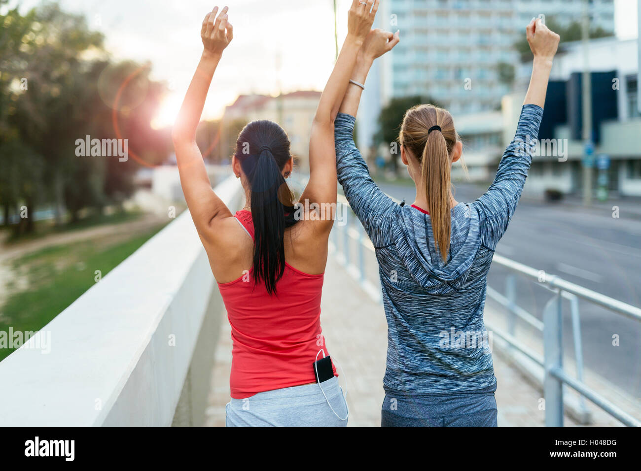 Two women happy after finishing exercises and lifting their hands Stock