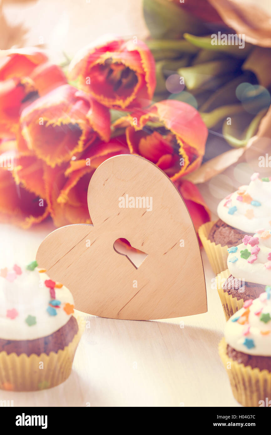 Delicious Mothers day  chocolate cupcakes  with spring tulips and wooden heart shape with free text space Stock Photo