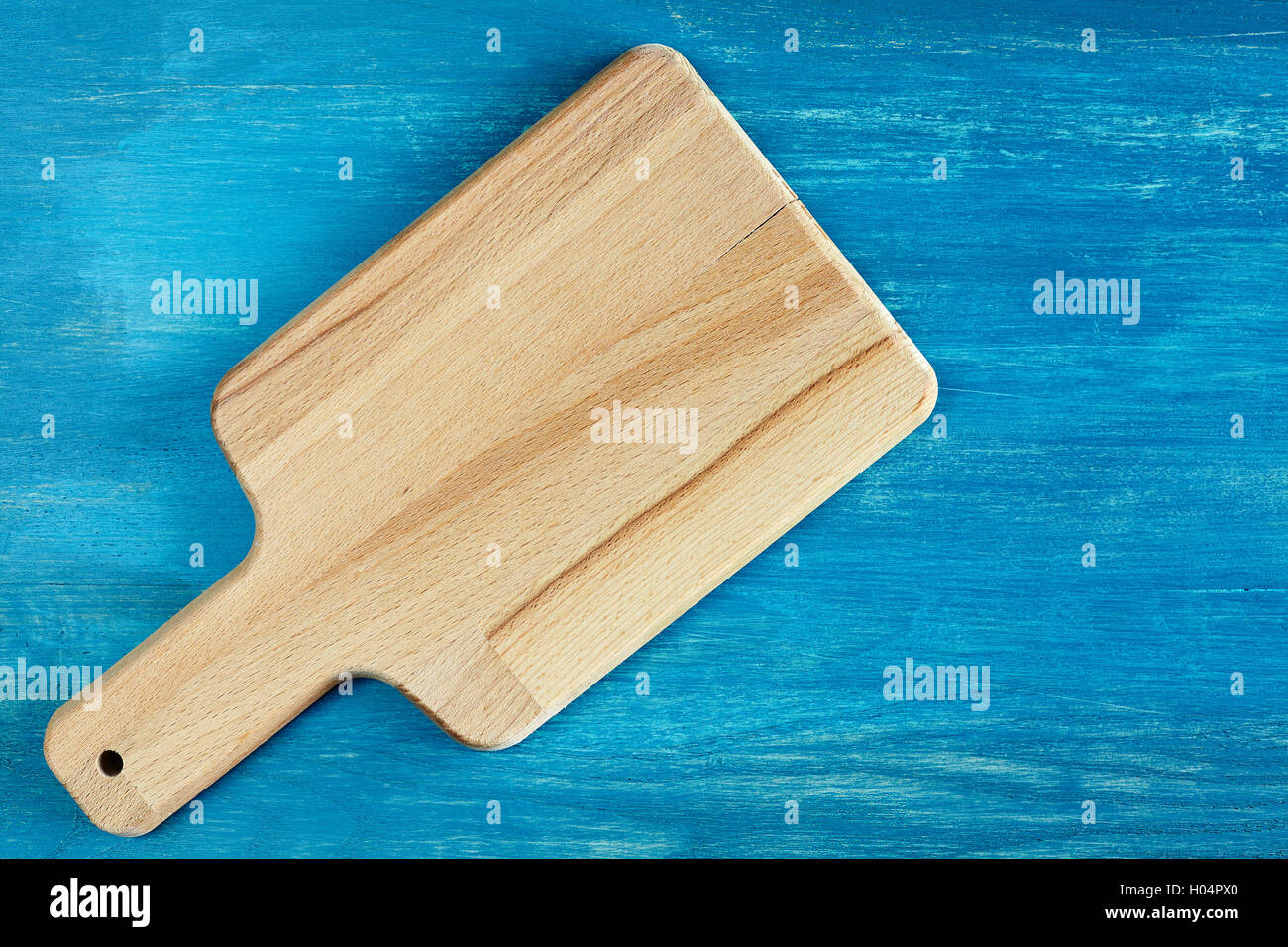 Empty wooden cutting board on rustic blue table, background with space for text, top view. Stock Photo