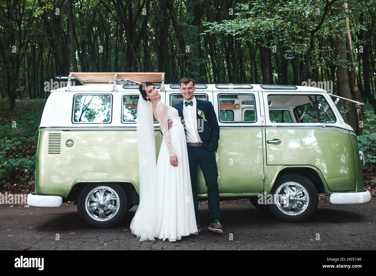 Bride and groom posing in front of car Stock Photo - Alamy