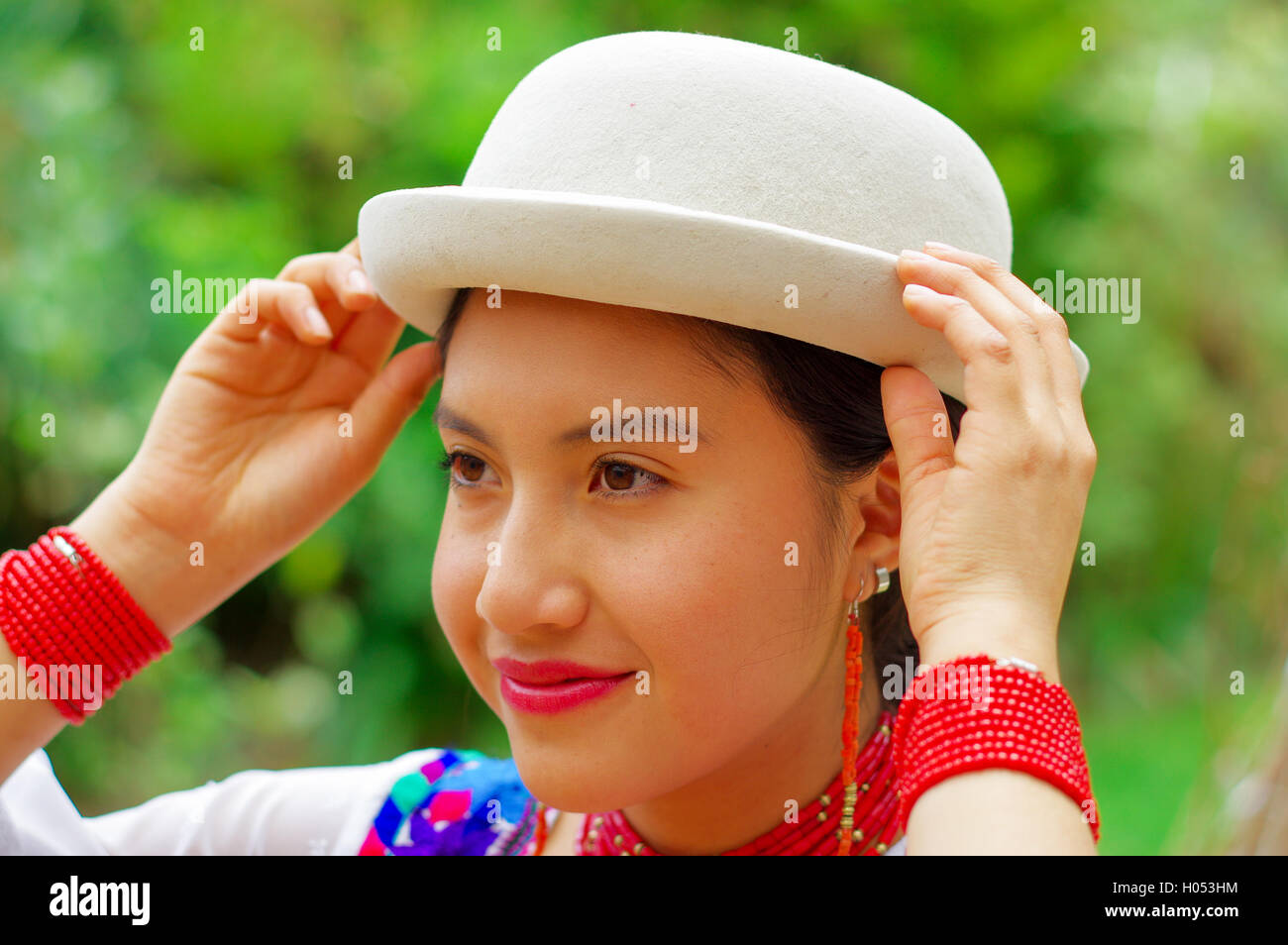 Headshot beautiful hispanic woman wearing, hat, traditional andean white blouse with colorful decoration around neck, matching r Stock Photo