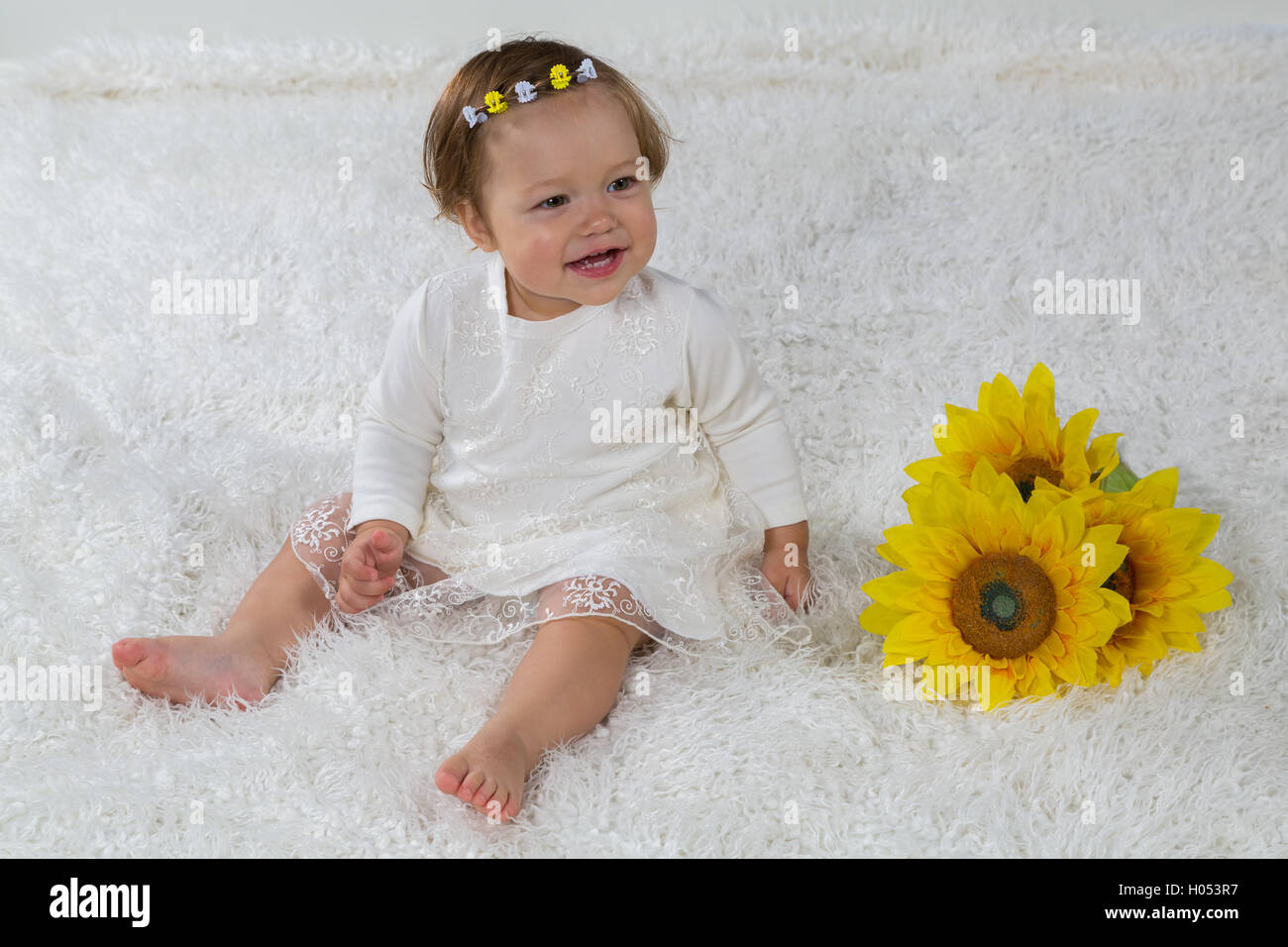 Little girl is sitting on the white carpet and laughs Stock Photo - Alamy