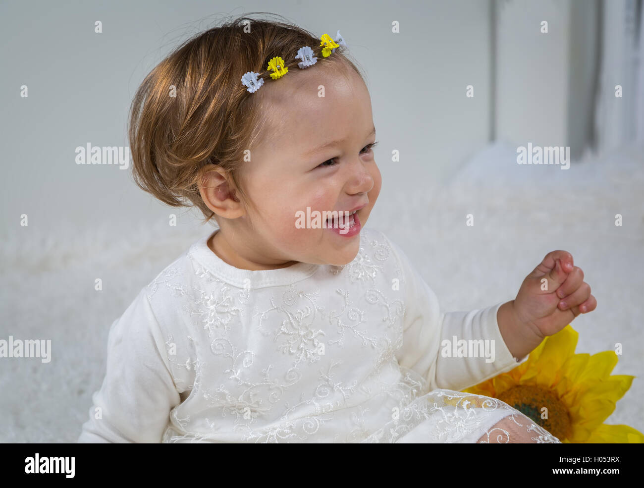 Little girl is laughing sitting on soft white carpet Stock Photo - Alamy