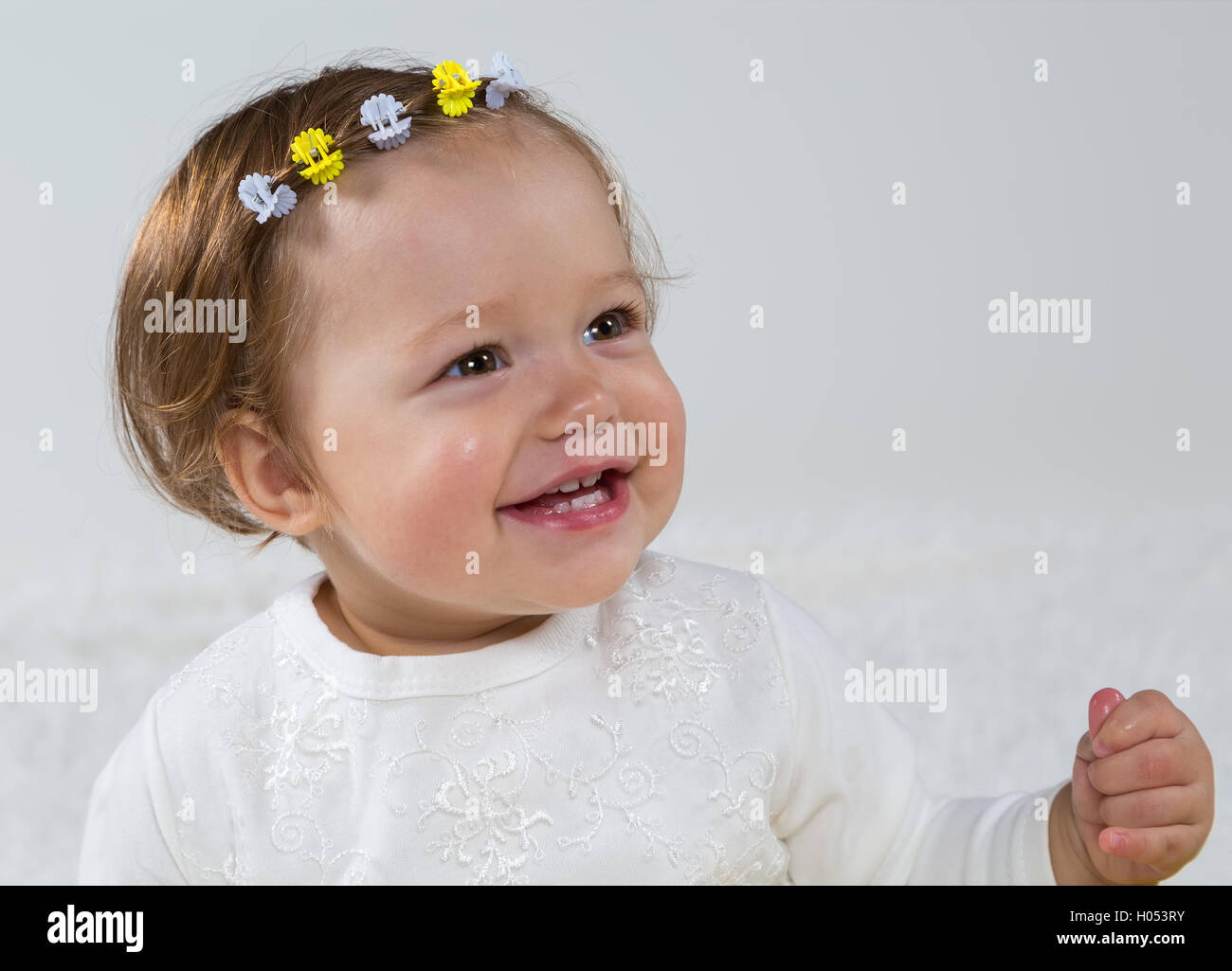 Little girl is sitting on the white carpet and laughs Stock Photo - Alamy