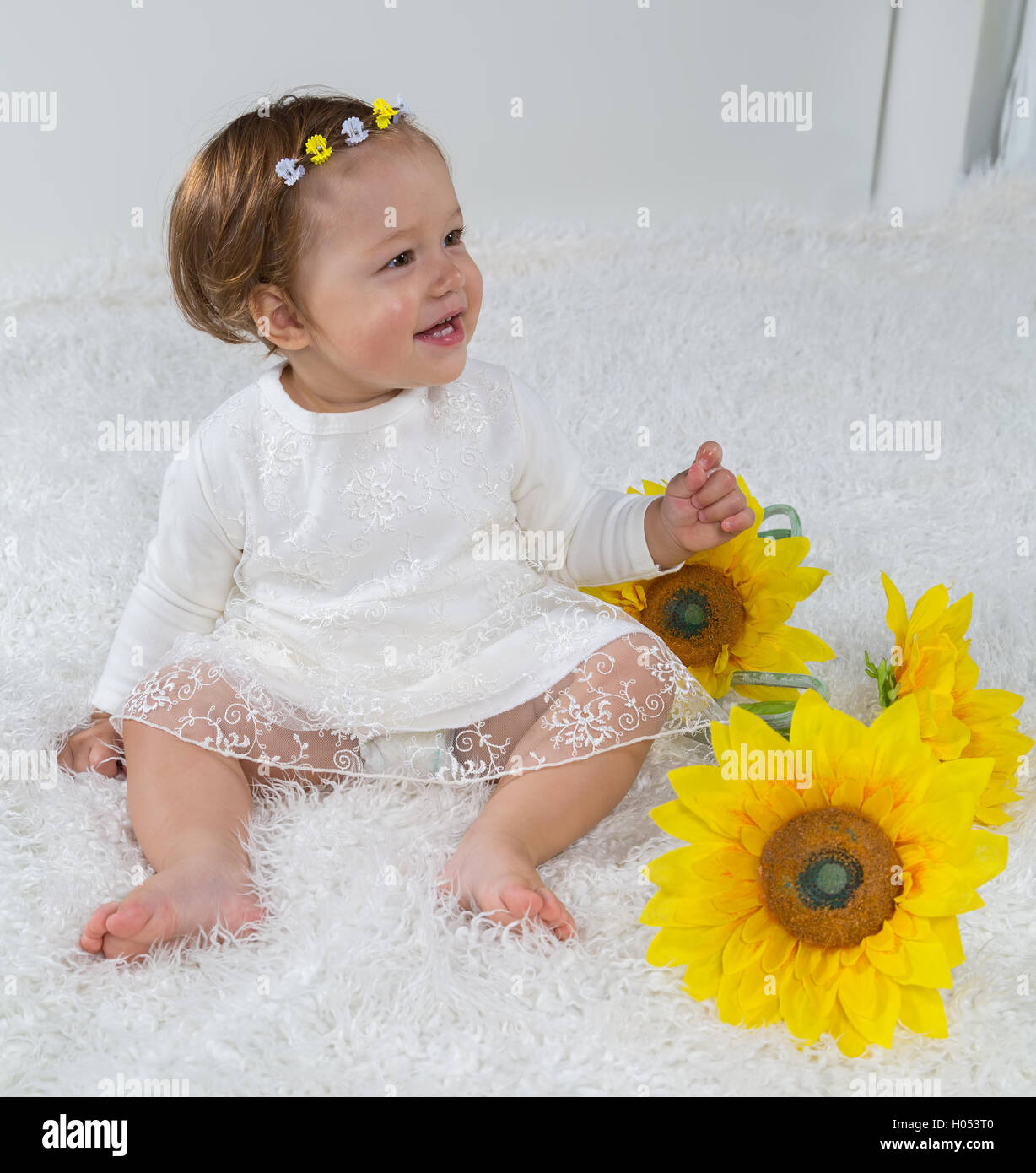 Little girl is sitting on the white carpet and laughs Stock Photo - Alamy
