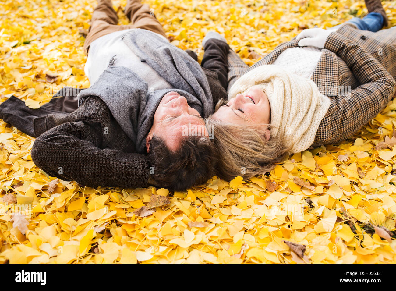 Active senior couple in autumn park lying on the ground Stock Photo - Alamy