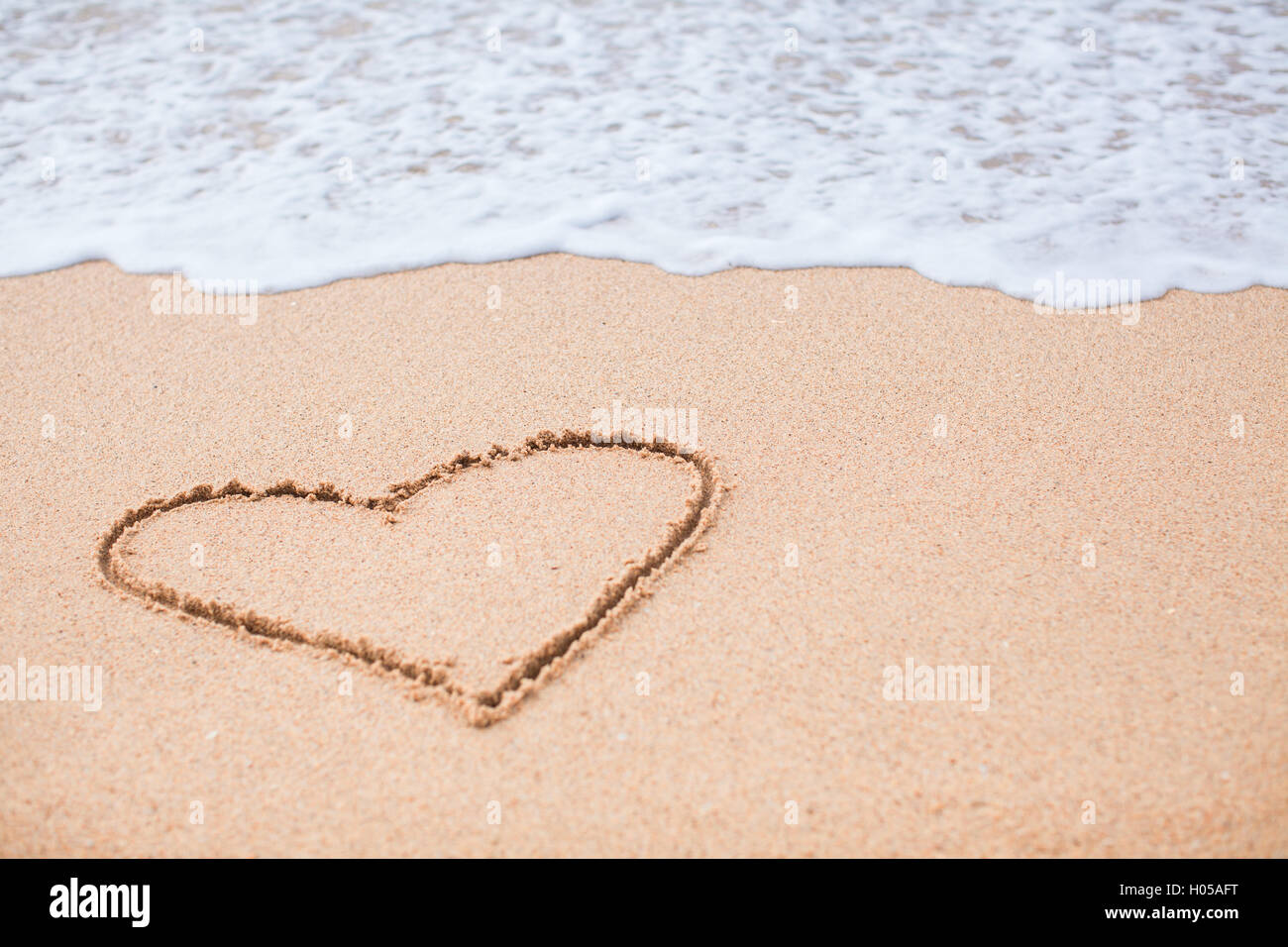 Heart painted in the sand on a tropical beach Stock Photo