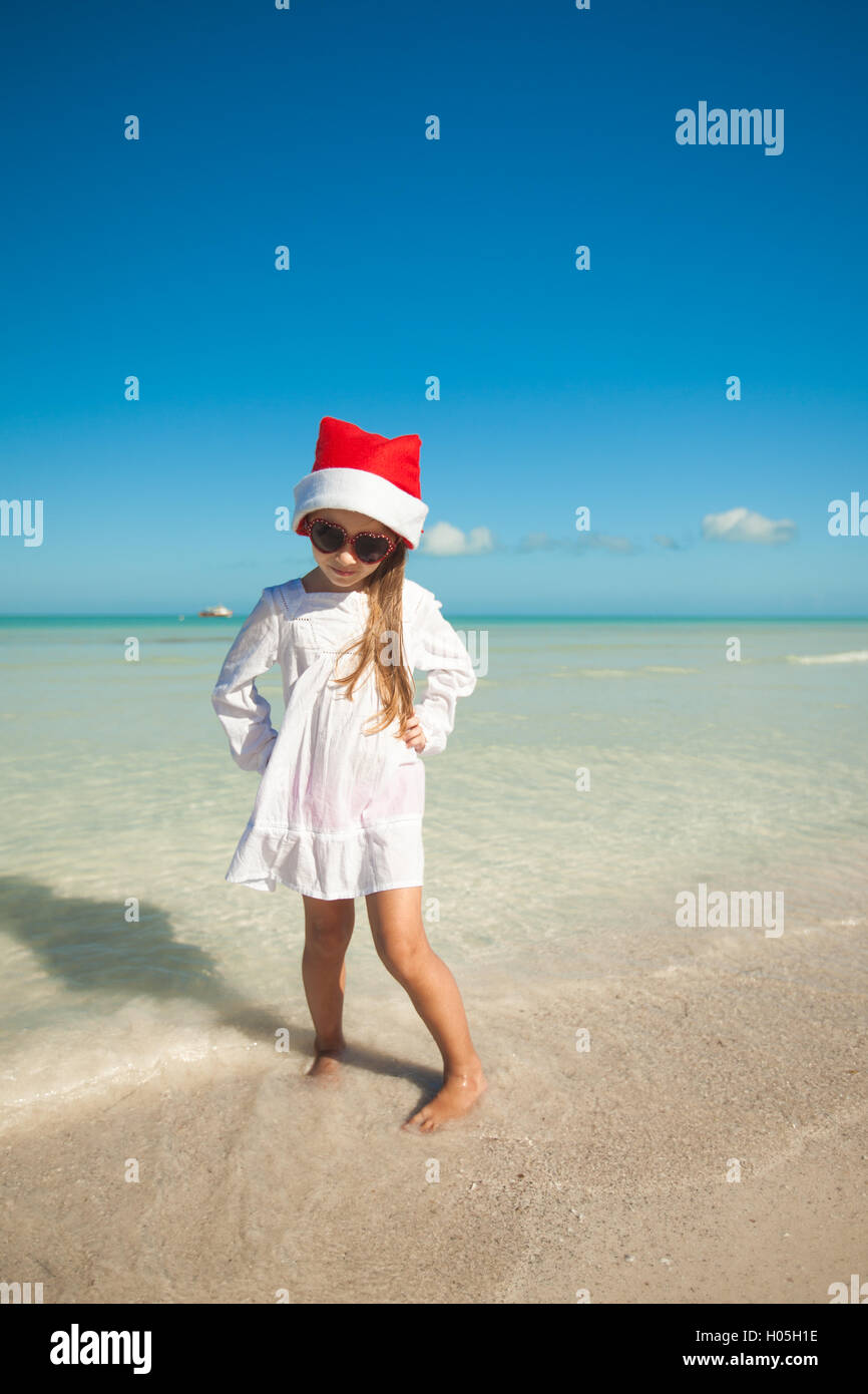 Little cute girl in red hat santa claus and sunglasses on the beach ...
