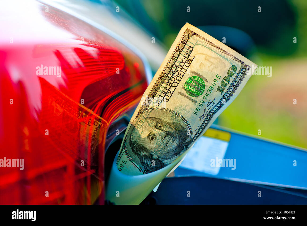 Hundred dollar bills in a vehicle fuel tank neck Stock Photo