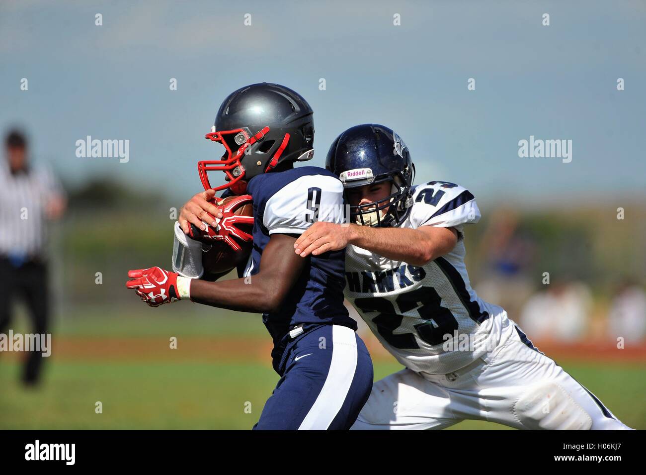 Defensive back wrapping up an opposing running back in making a solo tackle during a high school football game. USA. Stock Photo