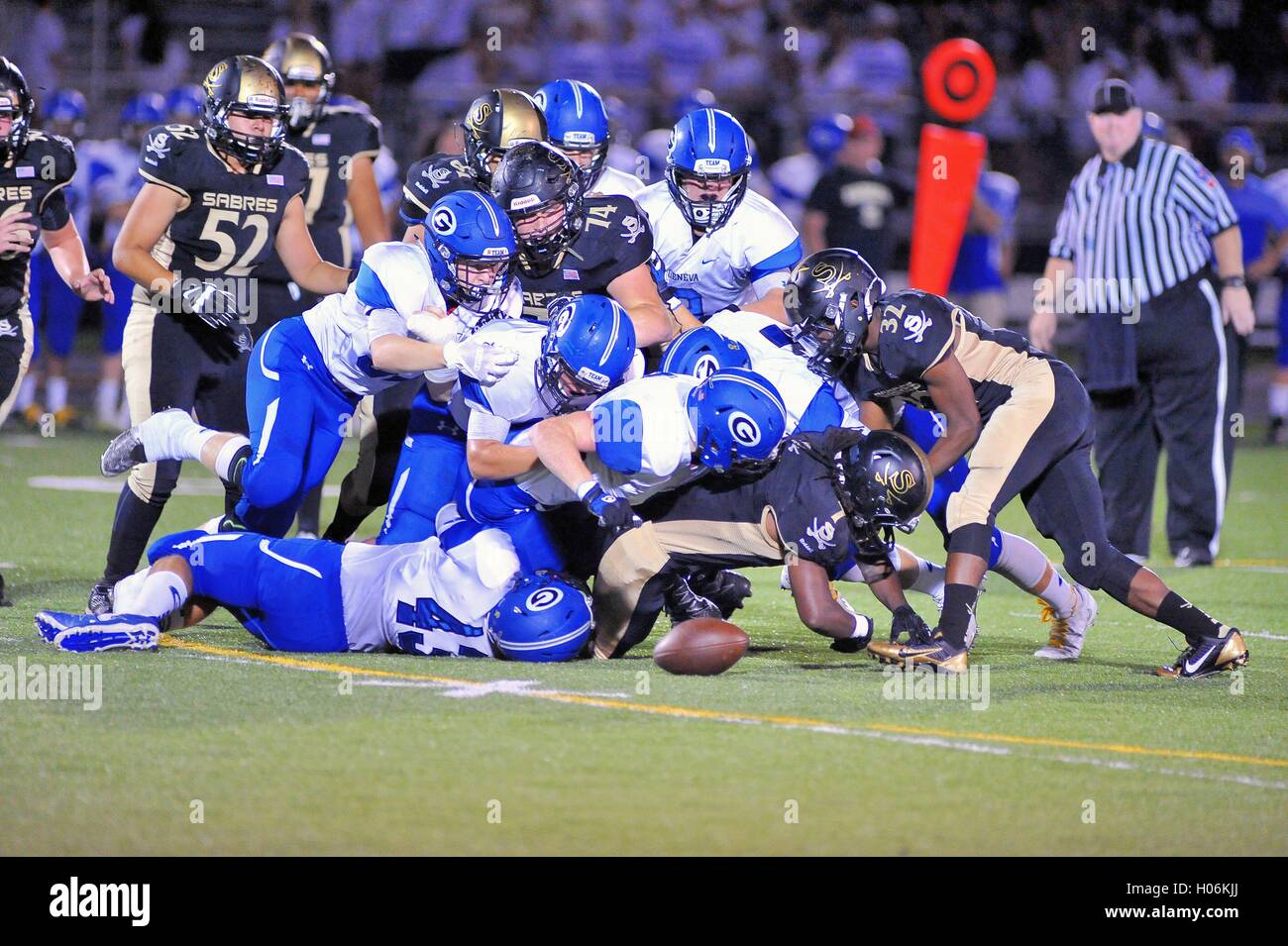 Running back fumbles while being hit by a wall of defenders during a high school football game. USA. Stock Photo