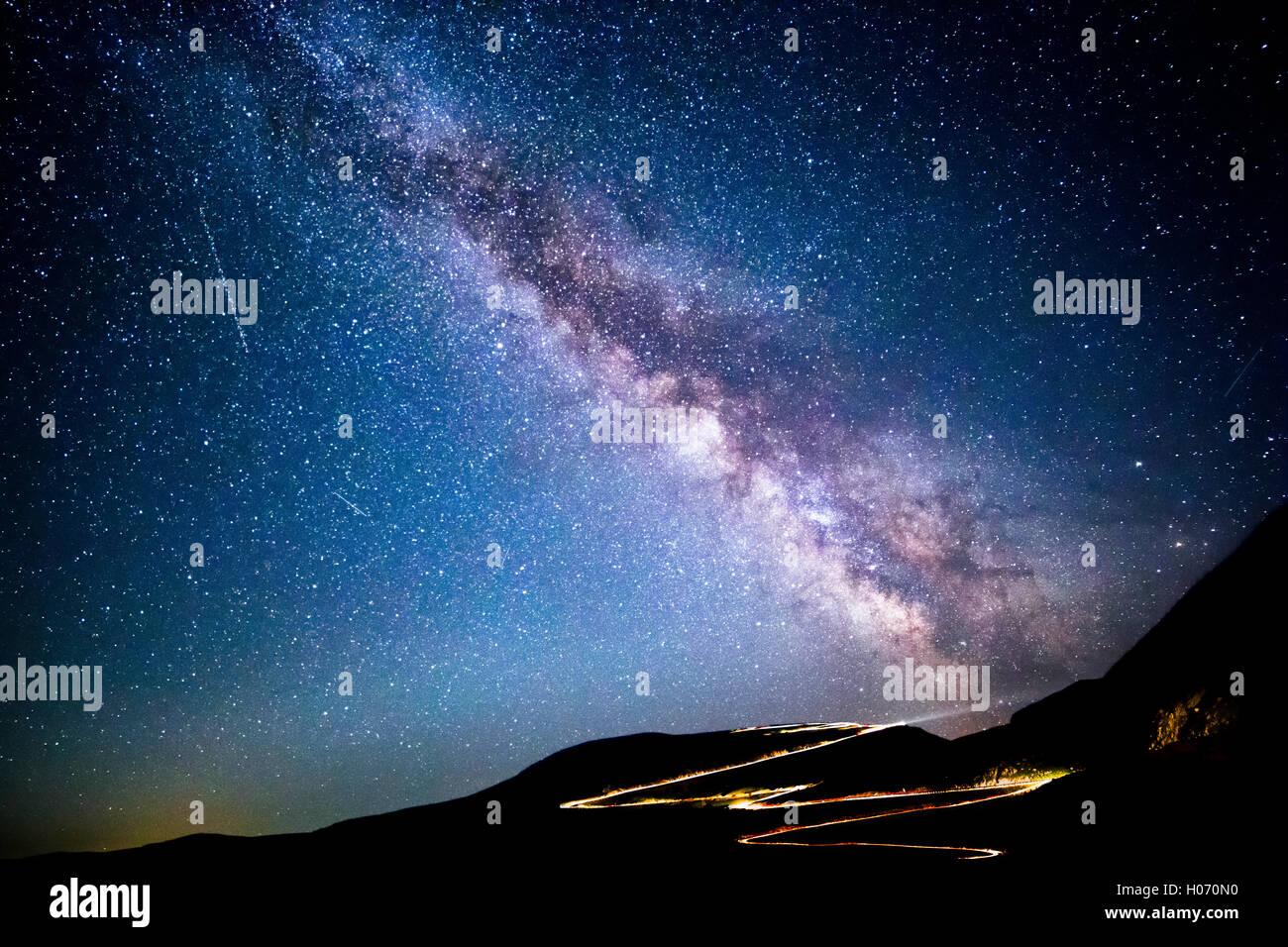 Milky way and traffic trails on Transalpina Carpathian pass, in Romania Stock Photo