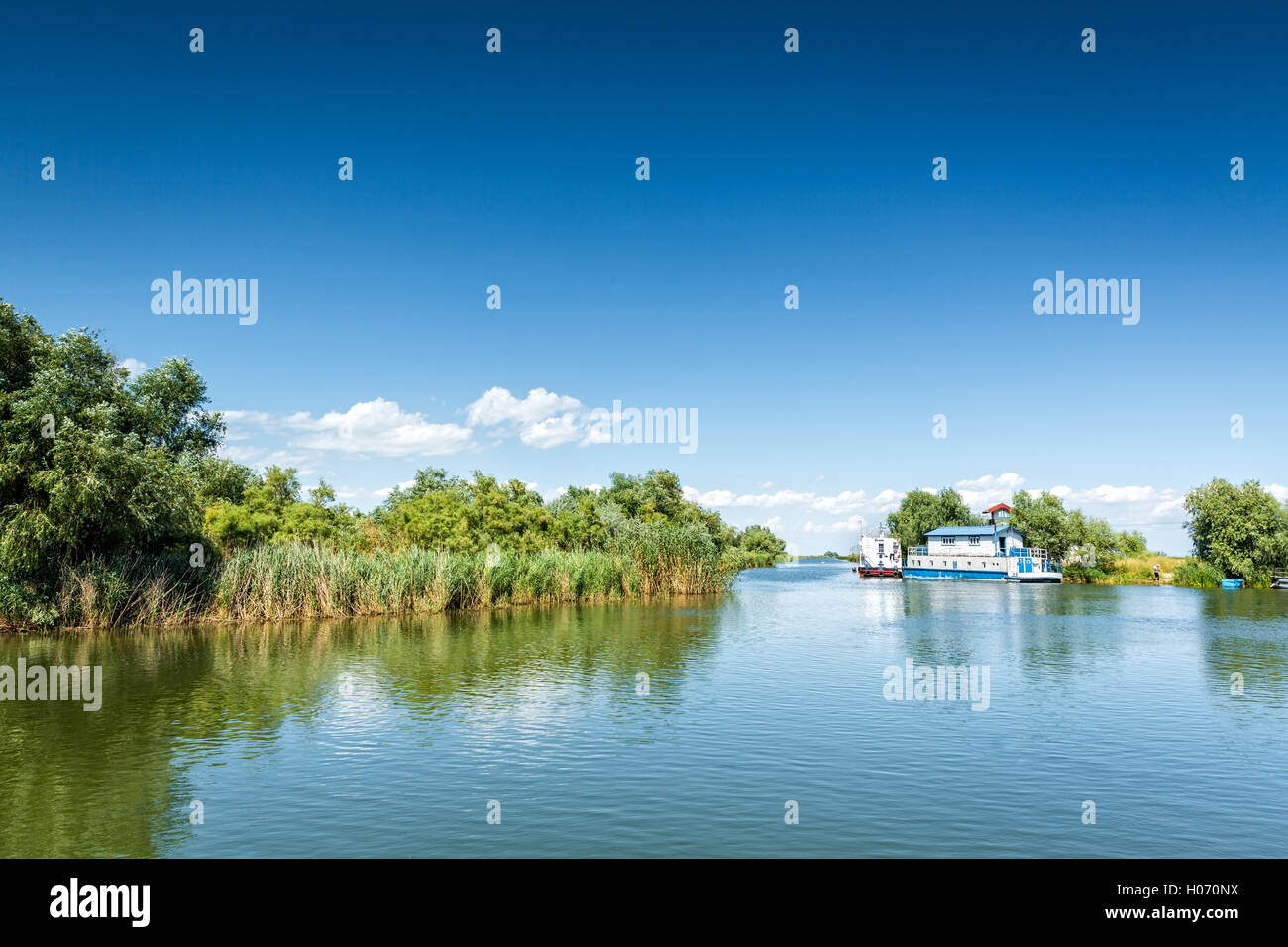 Typical Danube Delta landscape with lakes, canals and lush vegetation on a clear sunny day, in Gura Portitei resort, Romania Stock Photo