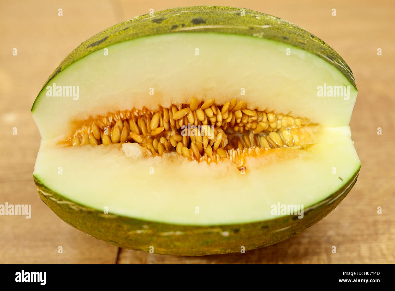 Toad skin melon halved on a wooden table. Stock Photo