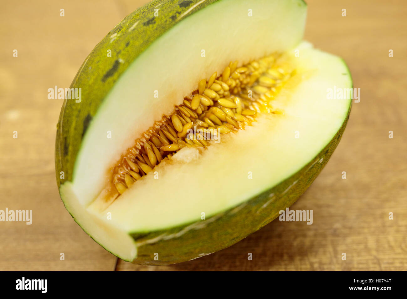 Toad skin melon halved on a wooden table. Stock Photo
