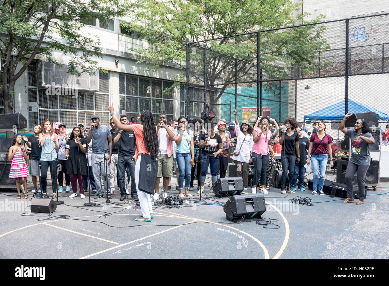 members of Times Square Church Gospel choir singing hearts out in free concert on playground of local vocational high school Stock Photo