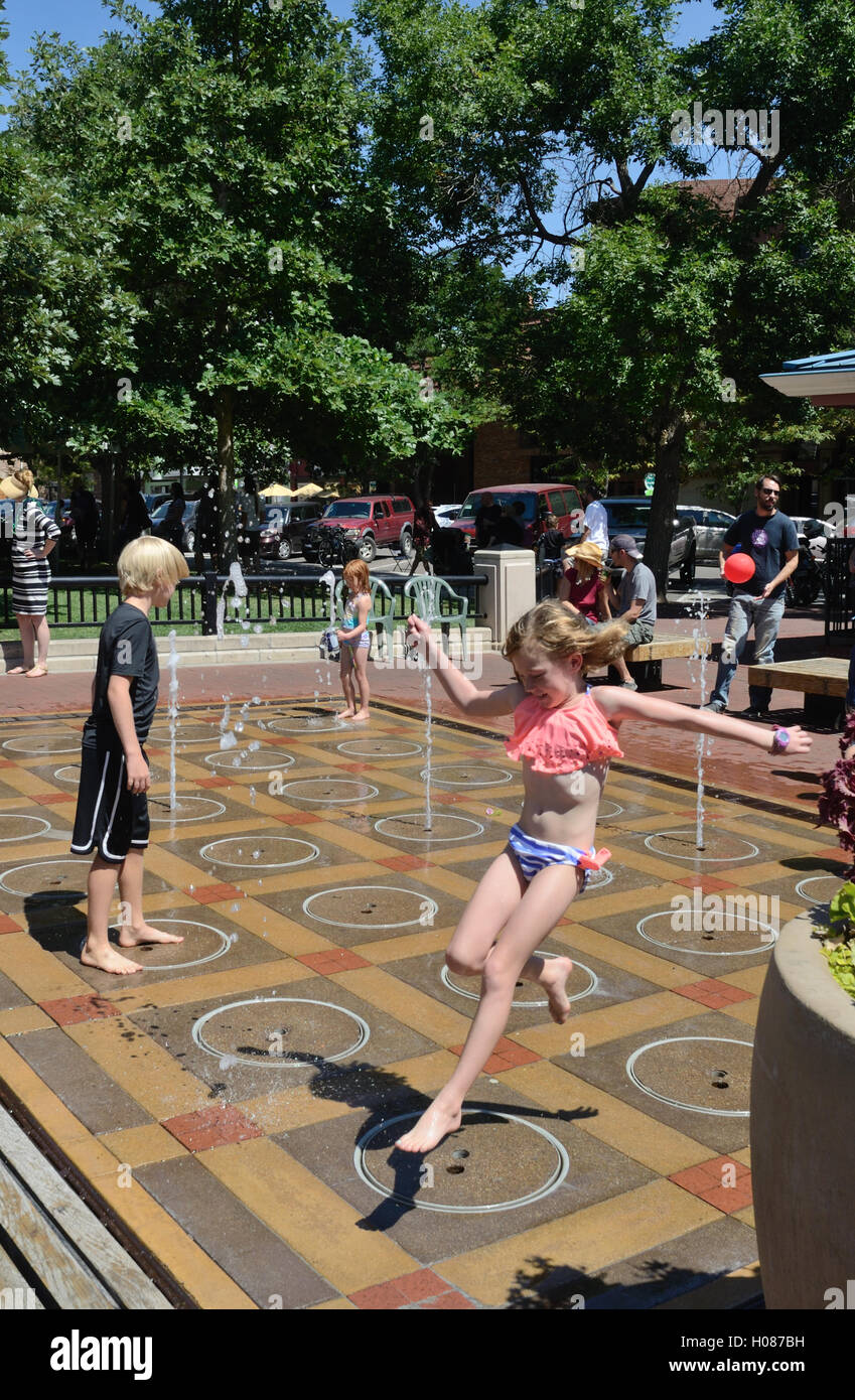 Girl jumps over water nozzle  at the children's water feature on Pearl Street Mall Stock Photo