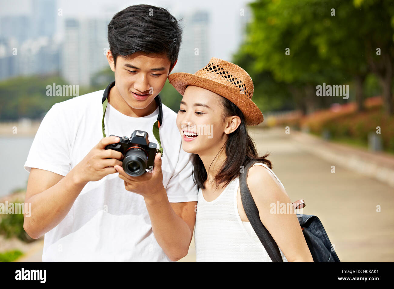 young asian couple tourists looking at camera's monitor checking pictures taken Stock Photo
