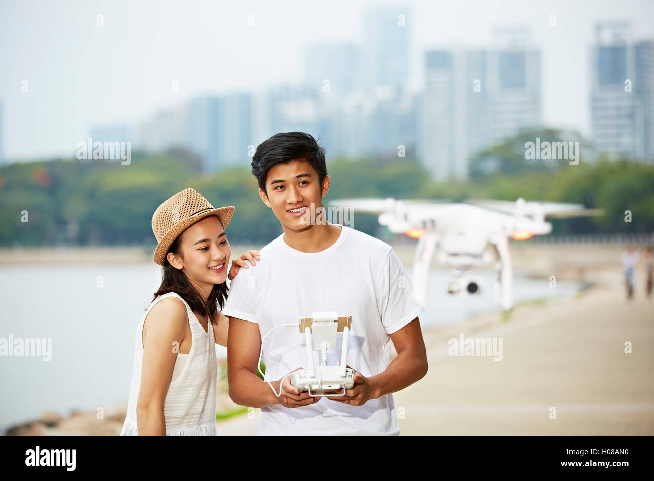 young asian couple operating a drone in a city park Stock Photo