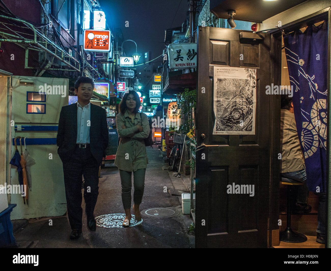 A man and a woman walk down Golden Gai a late night district  in Shinjuku which has the ambience of Showa era post war Tokyo Stock Photo