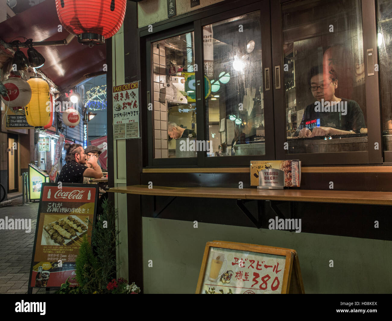 Patrons and cook, Izakaya bar, Ikebukuro, Tokyo, Japan, city street at night Stock Photo