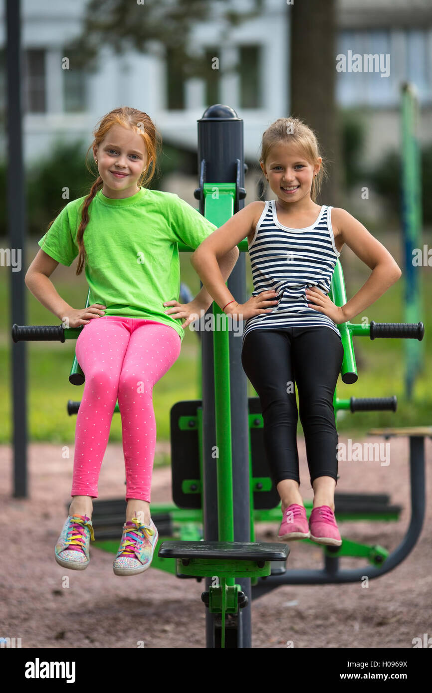 Two Little Girls And Sport Fitness Equipment On The Playground Stock Two Little Girls And Sport Fitness Equipment On The Playground Stock