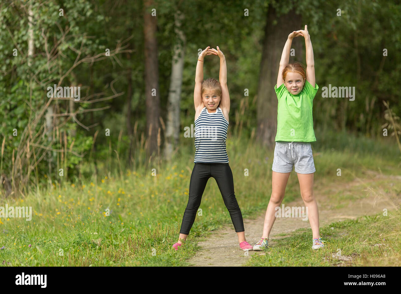 Two little girls perform gymnastic exercises outdoors Stock Photo Alamy