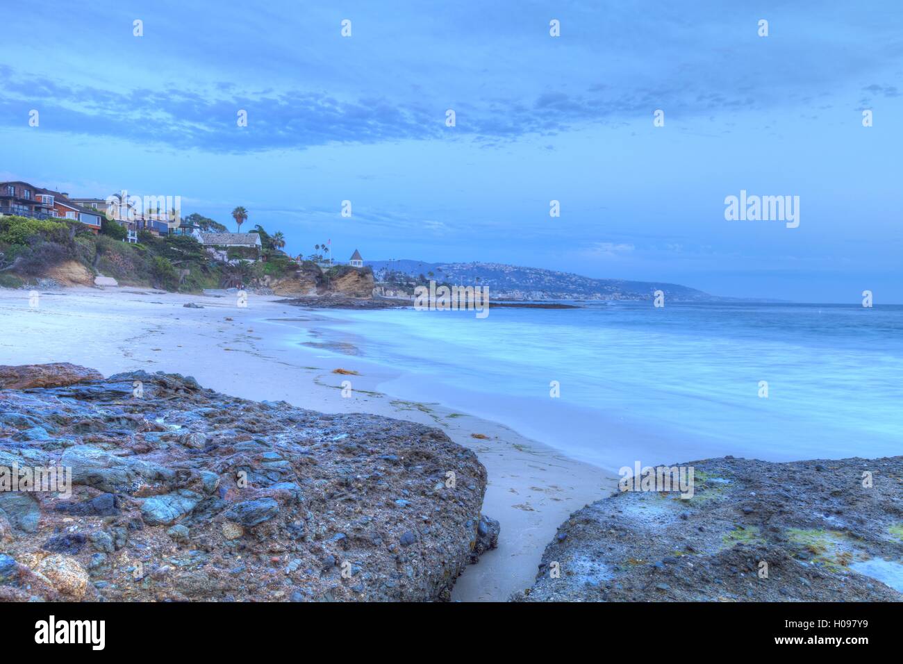 Sunset over the rocks at Shaws Cove in Laguna Beach as water flows over the stone in HDR Stock Photo